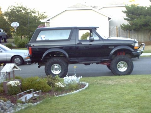 1995 Ford Bronco - Side view of a lifted 1995 Ford Bronco with black paint parked on a residential street.