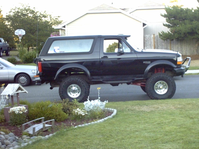 Black lifted two-door Ford Bronco SUV, driver-side view on a suburban driveway