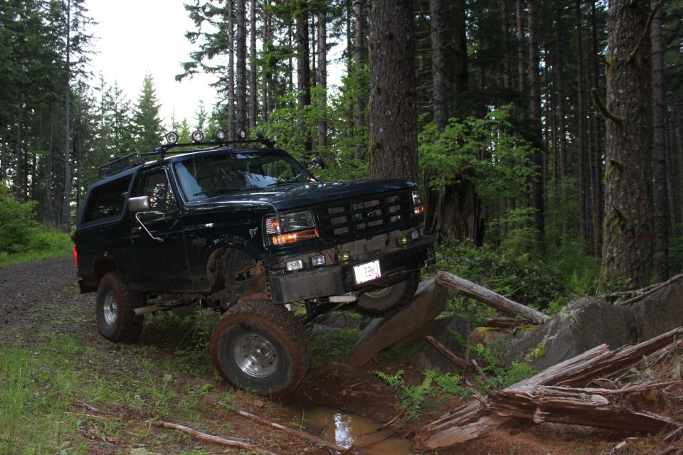 Black 1995 Ford Bronco navigating a rocky forest trail