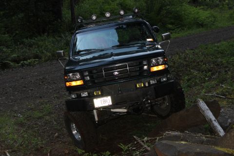 1995 Ford Bronco - This Ford Bronco is navigating an off-road trail with a large log in its path.