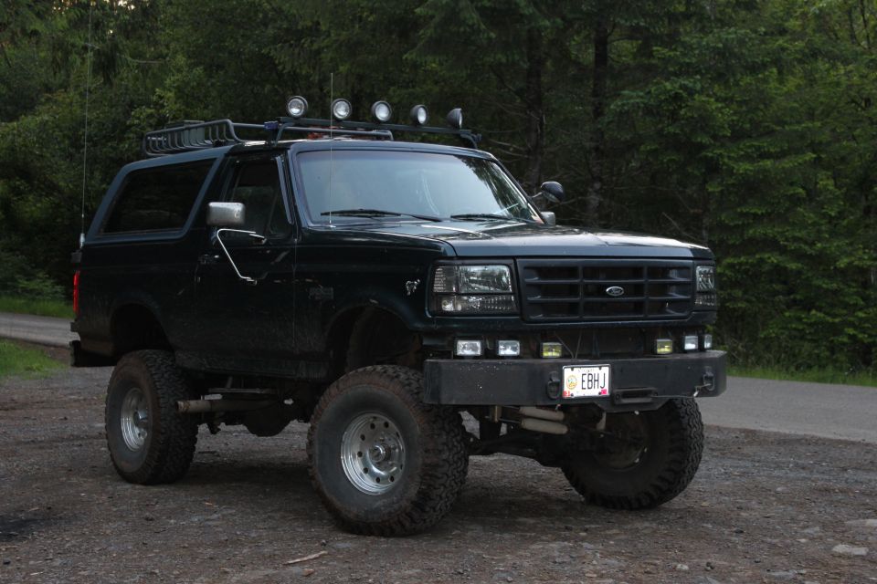 1995 Ford Bronco with roof rack and off-road tires parked on dirt road