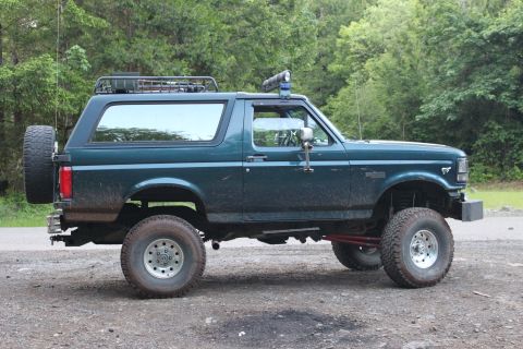 1995 Ford Bronco - This lifted Ford Bronco, seen from the side, has a roof rack and a spare tire mounted on the rear.
