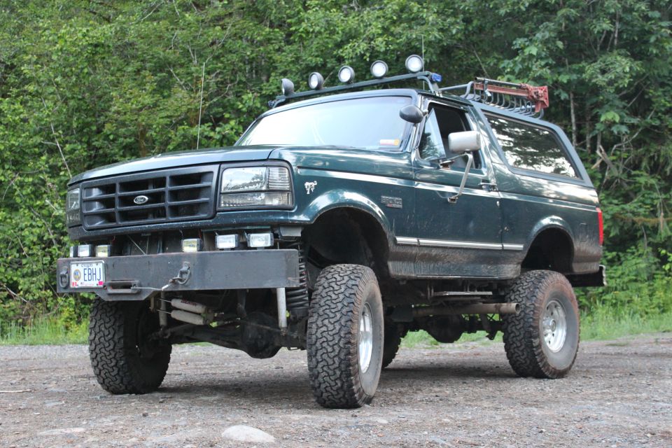 Green lifted Ford Bronco with roof lights and a rack. License plate reads EBHJ