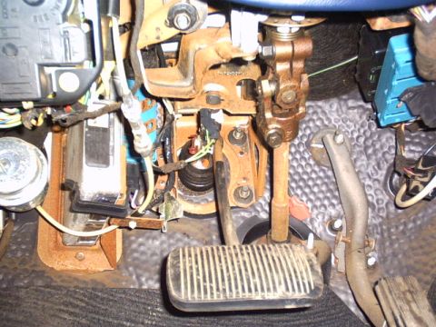 1991 Ford LTD Crown Victoria - Under-dash view from the driver's footwell showing the rubber-padded brake pedal, surface-rusted pedal support bracket and steering column…