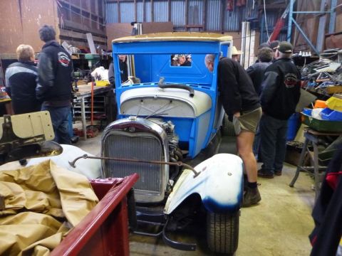 1969 Lincoln Continental - Workshop scene with a vintage truck undergoing restoration, several people observing.
