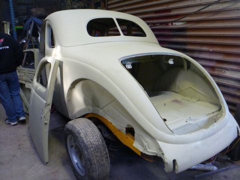 1969 Lincoln Continental - A vintage car body, prepped for restoration, sits in a workshop with its doors ajar.