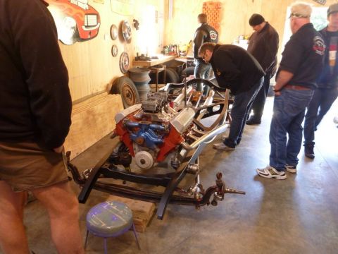 1969 Lincoln Continental - Workshop scene with a car chassis and engine, observed by several people.