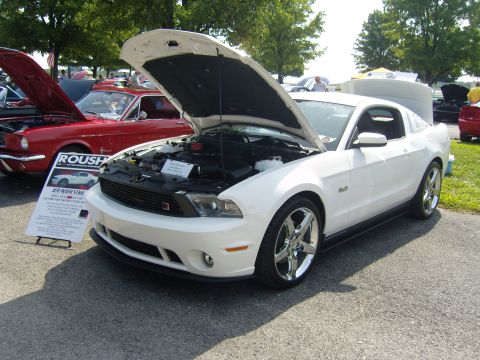 2007 Ford Mustang - A white Ford Mustang is displayed with its hood open, alongside a red classic car at an outdoor event.