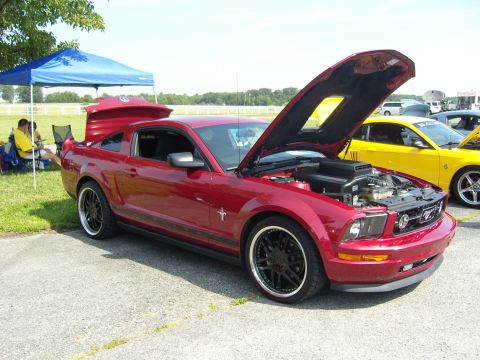 2007 Ford Mustang - A red Ford Mustang is parked with its hood and trunk open, alongside a yellow vehicle.
