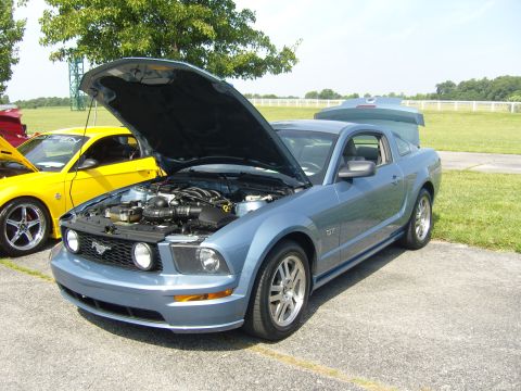 2007 Ford Mustang - A blue Ford Mustang GT is parked with its hood and trunk open, alongside a yellow vehicle.