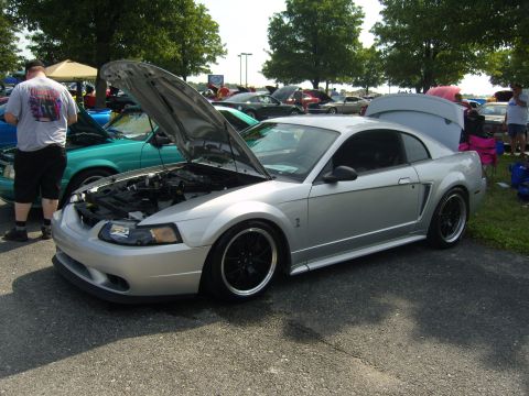 2007 Ford Mustang - A silver 2007 Ford Mustang is displayed with its hood and trunk open, surrounded by other vehicles and spectators.
