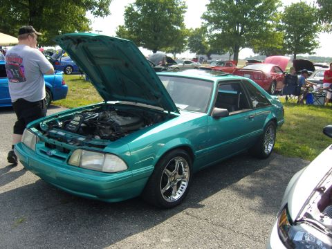 2007 Ford Mustang - A teal Ford Mustang from the late 80s or early 90s is displayed with its hood up at an outdoor event.