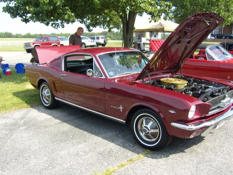 2007 Ford Mustang - A classic red 1965 Ford Mustang fastback is displayed with its hood open, revealing the engine compartment.