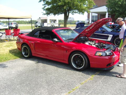 2007 Ford Mustang - Red 2007 Ford Mustang convertible at a car show with hood open, another Mustang nearby.
