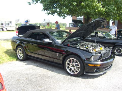 2007 Ford Mustang - Black 2007 Ford Mustang convertible at a car show, hood open showing the engine.
