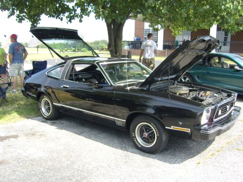 2007 Ford Mustang - A black 1970s Ford Mustang fastback is displayed with its hood and trunk open, parked outdoors.