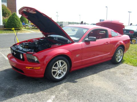 2007 Ford Mustang - A red 2007 Ford Mustang GT is displayed with its hood and trunk open, revealing the engine and interior.