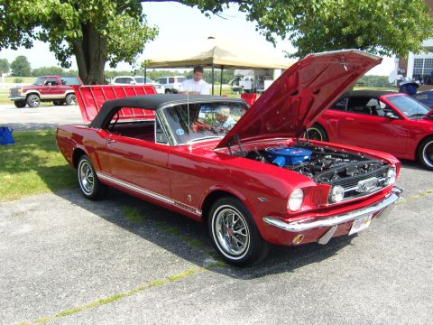 2007 Ford Mustang - A classic red Ford Mustang convertible is displayed with its hood open, revealing the engine bay.