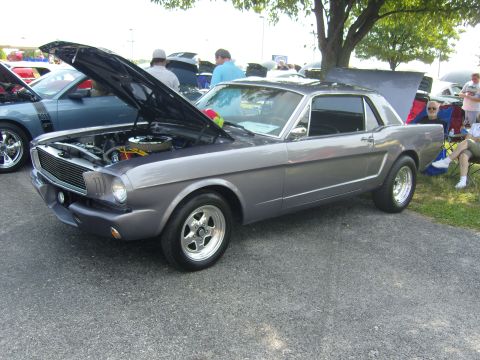 2007 Ford Mustang - A classic gray Ford Mustang coupe is displayed with its hood open at a car show, revealing the engine compartment.