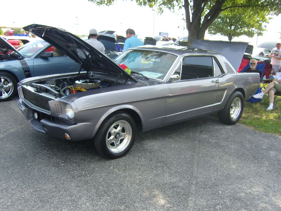 Gray 1965 Ford Mustang coupe, hood open, showing engine. Classic car show