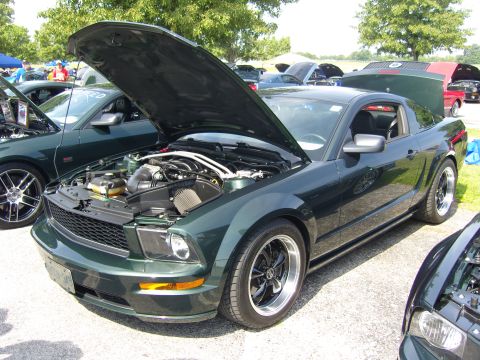2007 Ford Mustang - A dark green coupe with its hood open, revealing the engine bay, is parked outdoors.