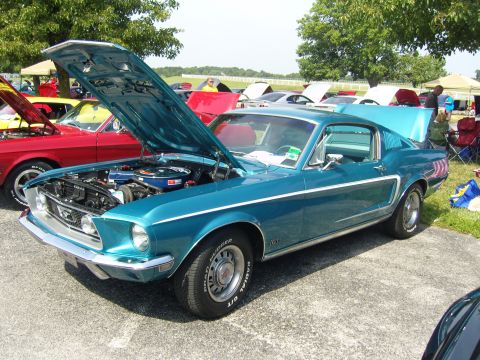2007 Ford Mustang - A teal 1967 Ford Mustang fastback is displayed with its hood and trunk open at an outdoor car show.
