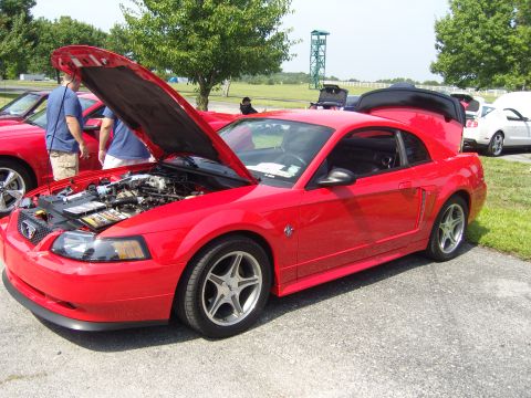 2007 Ford Mustang - A red Ford Mustang is displayed with its hood and trunk open, revealing the engine and interior at an outdoor car event.