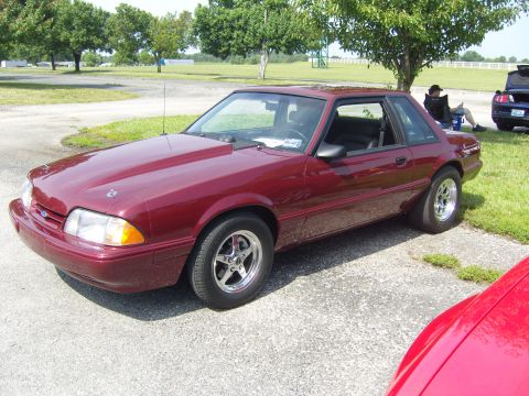 2007 Ford Mustang - This maroon Ford Mustang coupe features an aftermarket hood and drag-style rear tires.