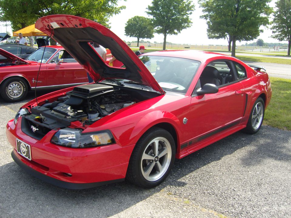 Red Ford Mustang coupe with hood open, showing engine. Black stripe along the side