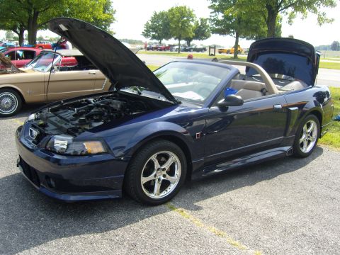 2007 Ford Mustang - A dark blue convertible with its hood and trunk open sits on asphalt with other vehicles in the background.