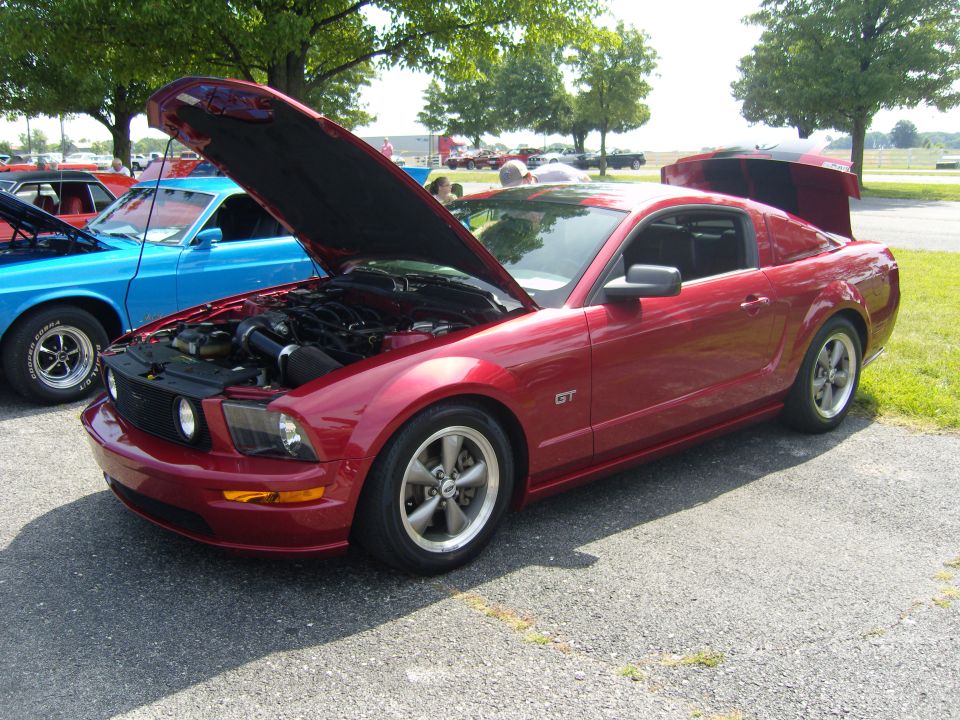 Red 2007 Ford Mustang GT parked outside with hood and trunk open, blue car in background