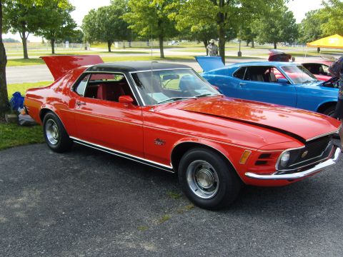 2007 Ford Mustang - A red 1970 Ford Mustang Mach 1 is parked next to a blue Mustang at a car show.