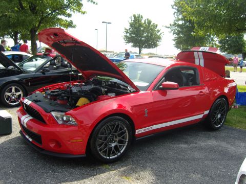 2007 Ford Mustang - A red Ford Mustang GT500 is displayed with its hood and trunk open, revealing its engine and rear storage.