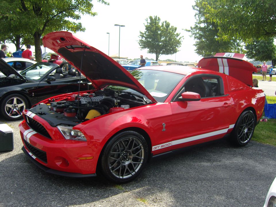 Red Ford Mustang GT500 with hood and trunk open, white racing stripes on hood and sides, black wheels
