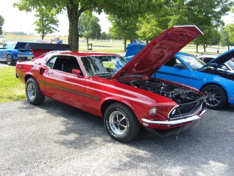 2007 Ford Mustang - A classic red 1969 Ford Mustang is displayed with its hood open, alongside newer models.