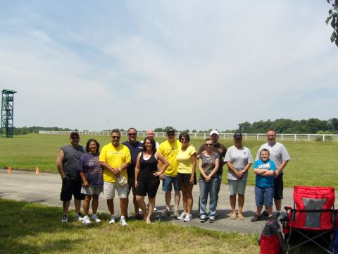 2007 Ford Mustang - A group of people pose for a photo outdoors on a sunny day with a tower structure visible in the distance.