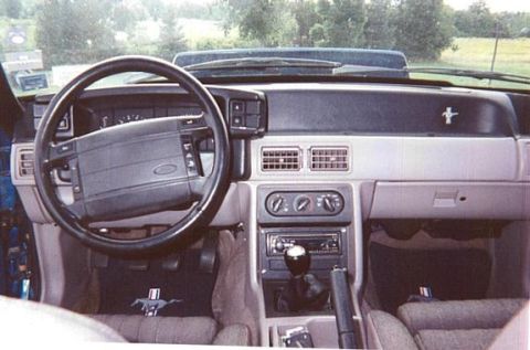 1990 Ford Mustang - The interior of a 1990 Ford Mustang, its dashboard, steering wheel, and center console.
