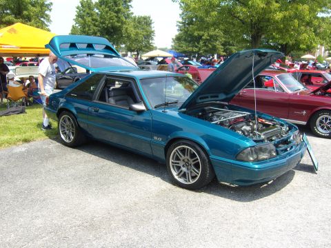 2007 Ford Mustang - A teal 1993 Ford Mustang coupe is displayed with its hood and trunk open at an outdoor car show.