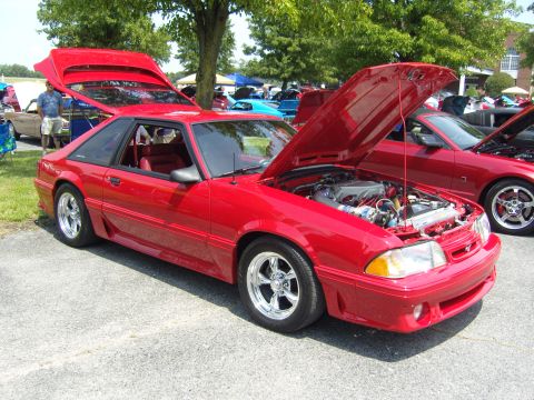 2007 Ford Mustang - Red coupe with hood and trunk open, parked outdoors with other vehicles.