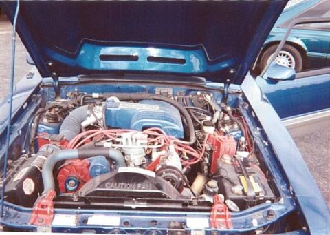 1990 Ford Mustang - Engine bay of a 1990 Ford Mustang, with a second Mustang visible in the background.