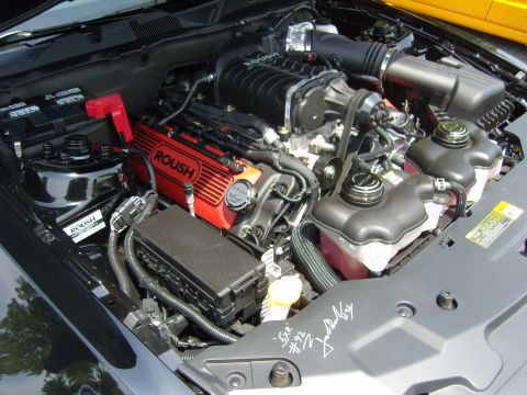 2007 Ford Mustang - Engine bay view of a ROUSH supercharged engine, red valve covers and a black intake system.