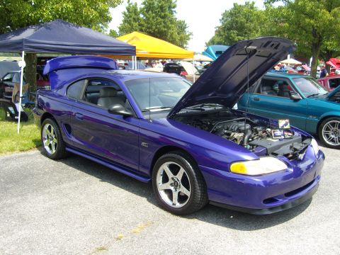 2007 Ford Mustang - A purple Ford Mustang is parked outside with its hood open, next to another car.