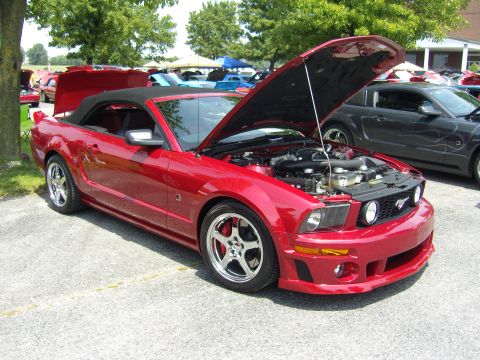 2007 Ford Mustang - A red 2007 Ford Mustang convertible is displayed with its hood open, revealing the engine compartment.