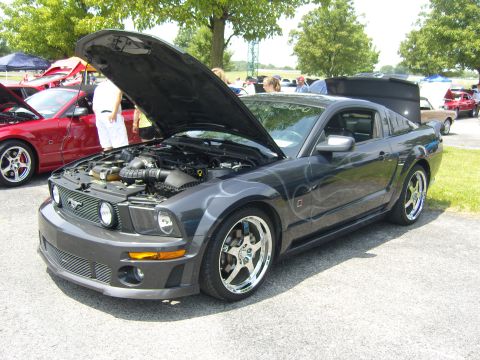 2007 Ford Mustang - A dark grey Ford Mustang is displayed with its hood open, revealing the engine compartment. Flame decals adorn its side.