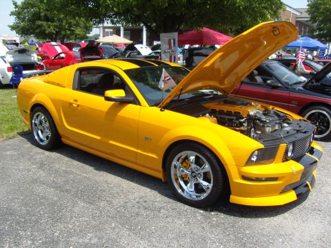 2007 Ford Mustang - A yellow Ford Mustang is displayed with its hood open at an outdoor car show.