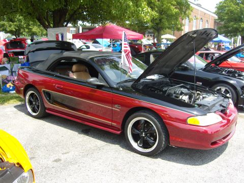2007 Ford Mustang - A red and black convertible Mustang is displayed with its hood open at an outdoor event.