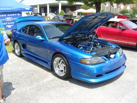 2007 Ford Mustang - A blue 1994 Ford Mustang coupe is displayed with its hood open, revealing the engine bay. Another Mustang is visible in the background.