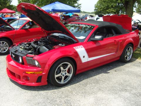 2007 Ford Mustang - A red convertible with its hood and trunk open is parked at an outdoor event.