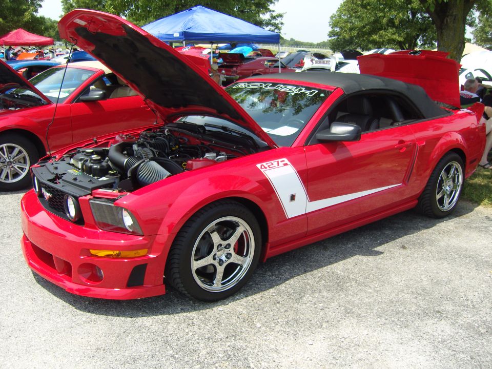 Red convertible with white stripe and '427' badging, hood and trunk open, parked outdoors