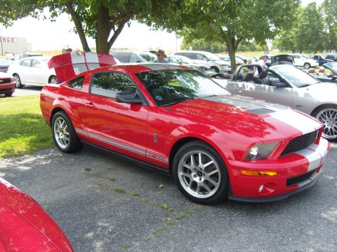 2007 Ford Mustang - Red 2007 Ford Mustang Shelby GT500 with racing stripes and trunk open.
